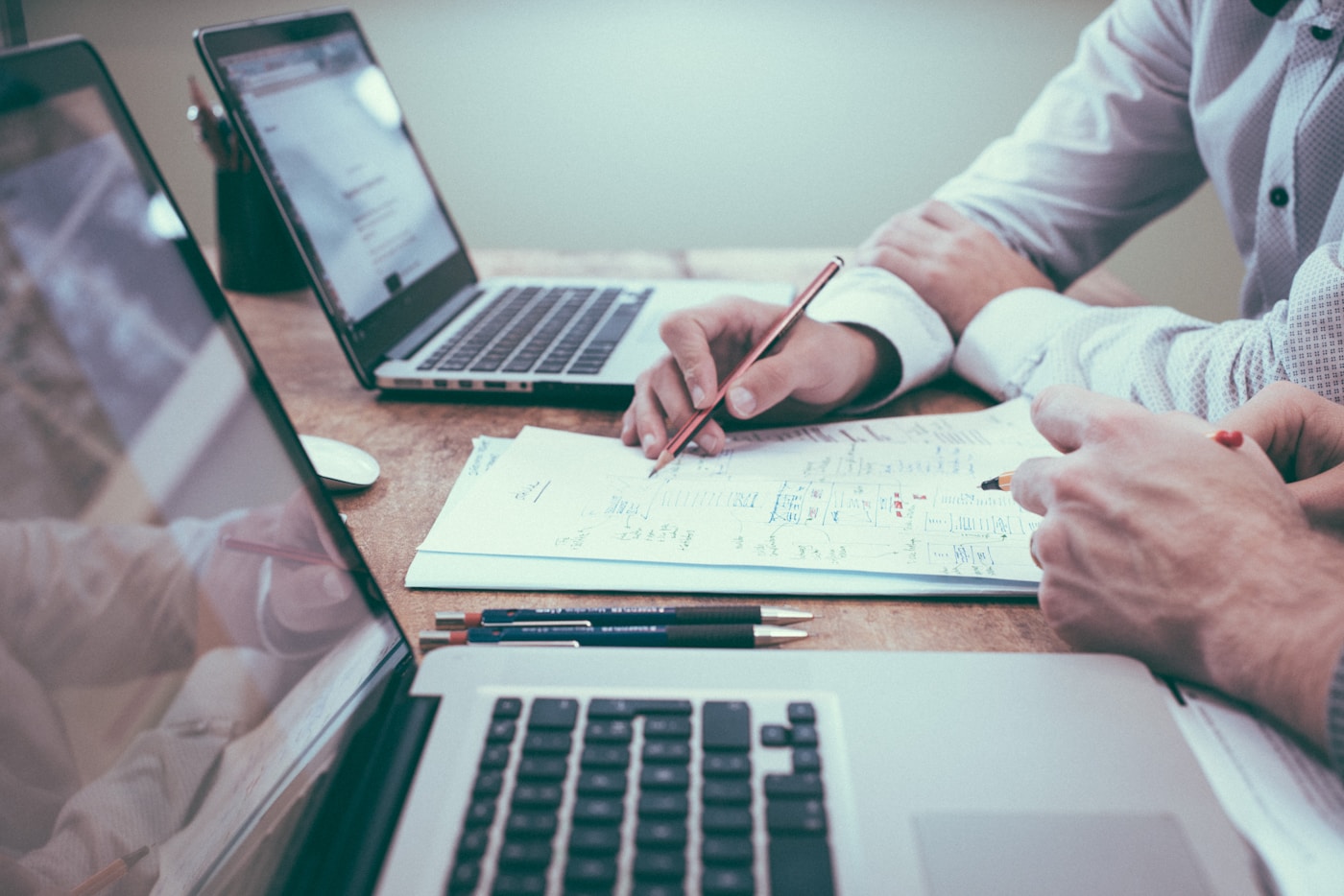 Two professionals reviewing data reports and documents at a desk during a client meeting